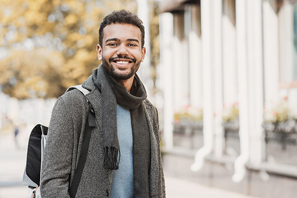 handsome joyful man in a city during autumn wearing warm clothes