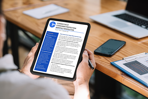 Stock image of a persons hands holding a tablet that is displaying an edition of the DCP newsletter