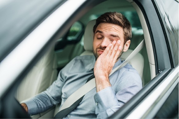 sleepy driver scratching their eyes while driving - drowsy driving violations