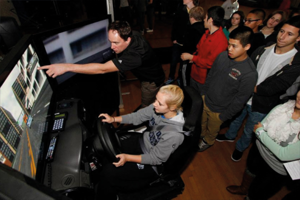 Group watching someone driving a simulator in save a life program