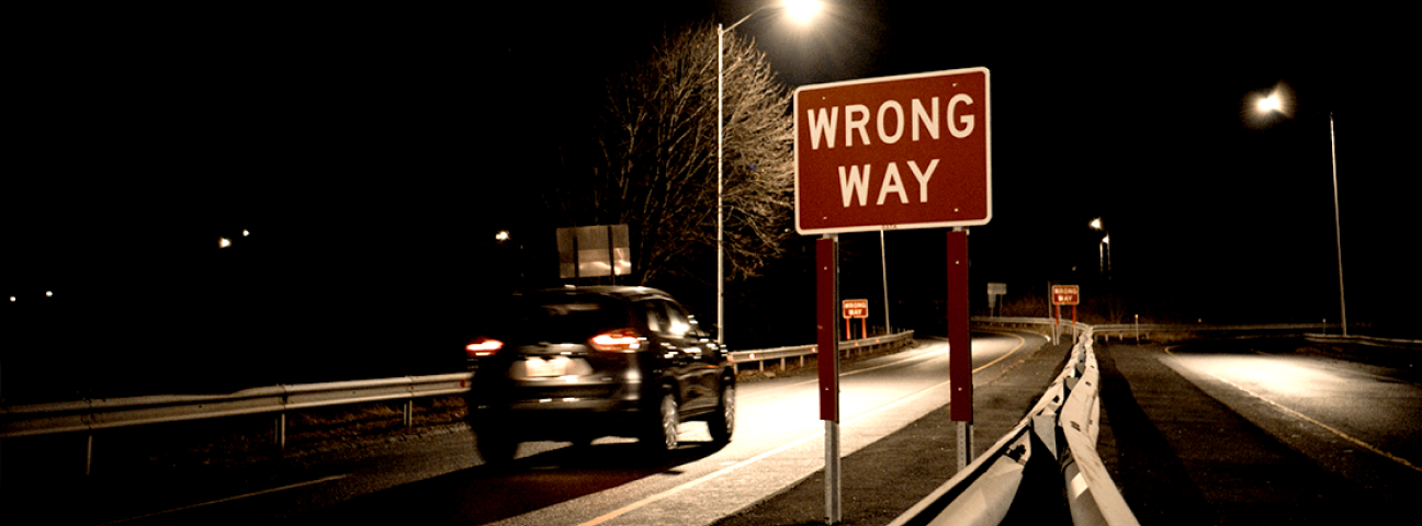 a car driving past a wrong way sign oblivious
