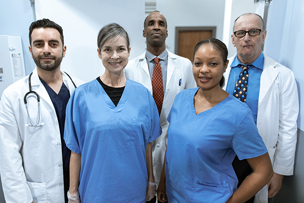 Group of five diverse healthcare professionals. Mixture of doctors in the back and nurses in the front.
