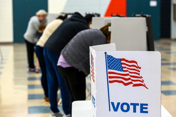 People standing at voting booths filling out ballots
