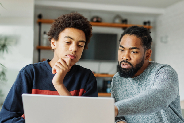 Father and son reading computer screen