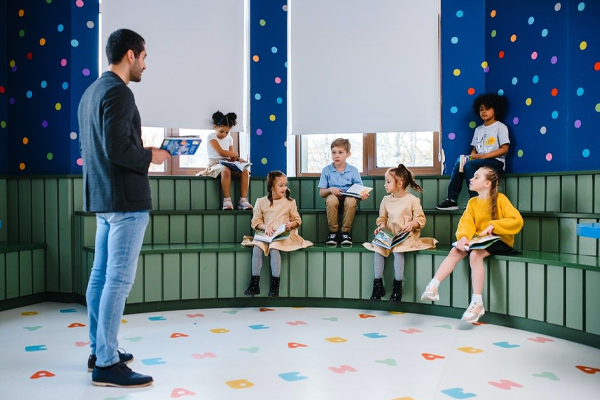 students sitting on green risers while their teacher talks to them