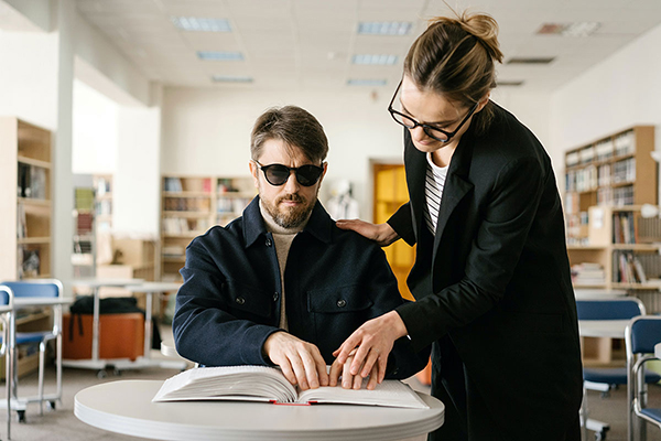 teacher helping young white blind man