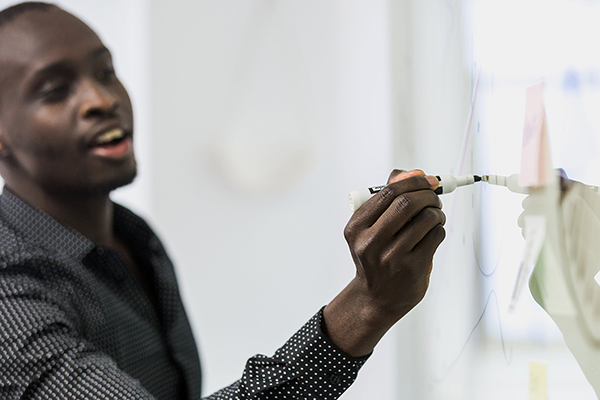 Young black male teacher writing on whiteboard